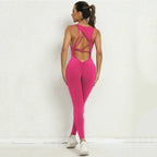 Yoga jumpsuit in vibrant pink with open crisscross back and snug fit for yoga or training sessions.
