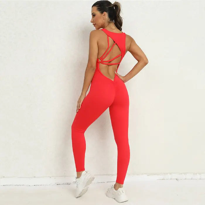 Yoga jumpsuit in red showing side-back angle with open strappy back and form-fitting silhouette.