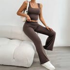 Woman wearing a brown yoga two-piece set while sitting on a modern white couch, showcasing stylish and comfortable activewear.