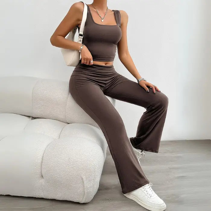 Woman wearing a brown yoga two-piece set while sitting on a modern white couch, showcasing stylish and comfortable activewear.