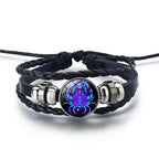 Zodiac Sign Bracelet featuring a luminous Cancer crab symbol in blue cosmic tones, paired with braided leather for a unique astrology jewelry piece.