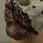 Zombie face mask displaying bloody mouth injury with torn flesh and red gore.