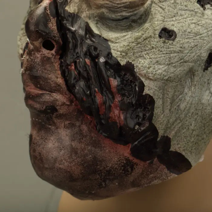 Zombie face mask displaying bloody mouth injury with torn flesh and red gore.